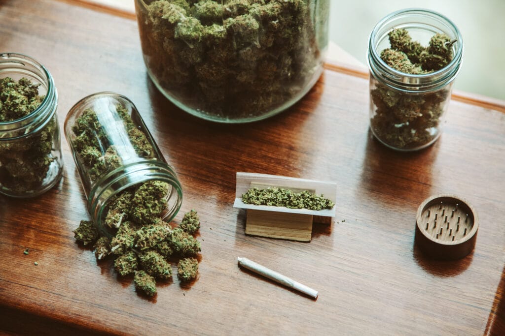 Cannabis flower in jars with a grinder and a rolled joint