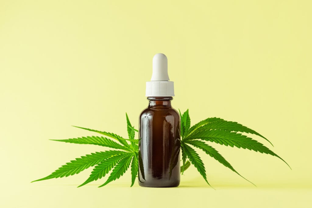 cannabis tincture with marijuana leaves on a yellow background